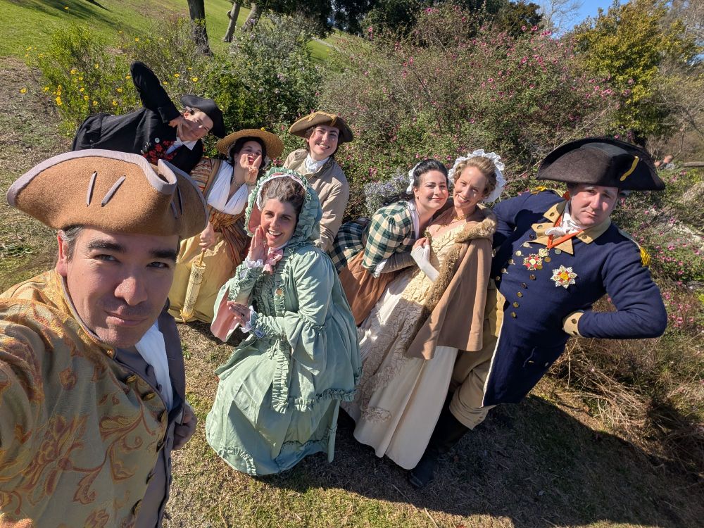 a group of people dressed in revolutionary war-era clothing, posing for a selfie
