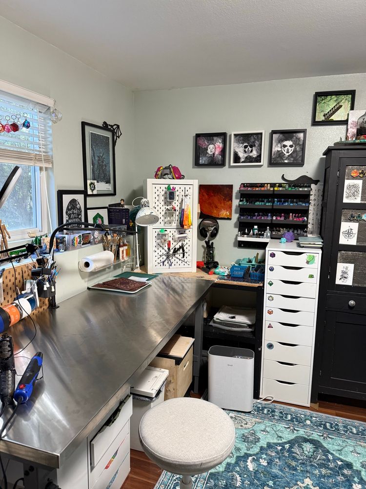 The corner of an art studio with storage, art, and a large steel work table. 