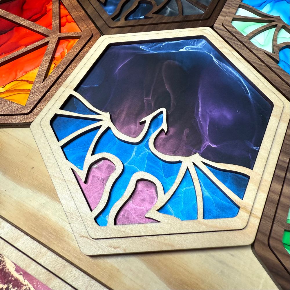 A hexagon wooden cutout with a dragon outline on top of a vibrant shimmering blue and pink painting. 