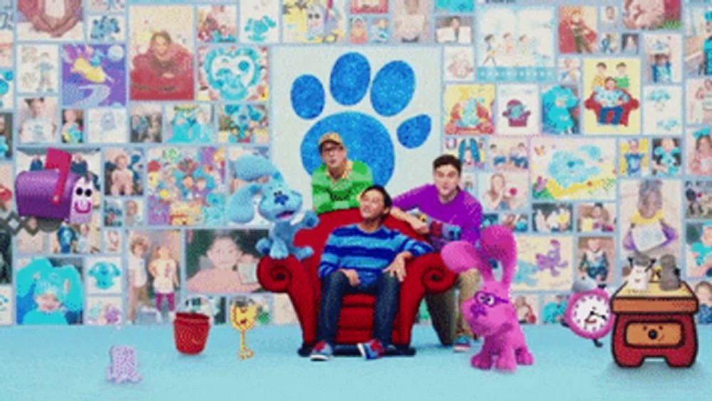 a group of people are sitting on a red couch in front of a wall with pictures of blue and friends