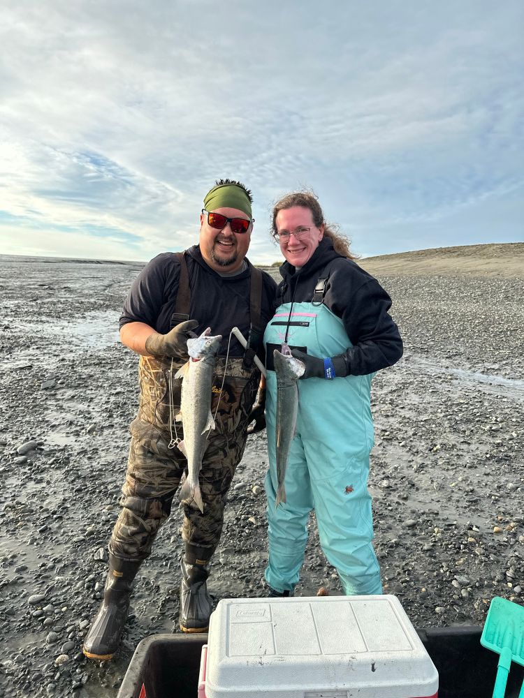 @lizinthelibrary and i holding red salmon from dipnet fishing. I’m wearing camouflage chest waders and she’s wearing blue chest waders. 