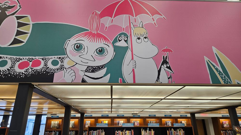 Moomins mural above the shelves in the children's book room of the library