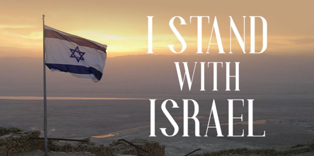 „I stand with Israel“ Schriftzug auf einem Landschaftsfoto mit wehender Israelfahne