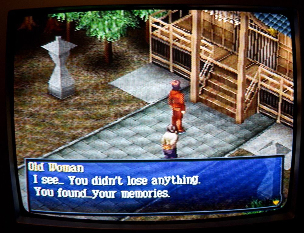 Picture of a CRT screen playing the beginning of Persona 2 Eternal Punishment. An old woman talks to Tatsuya outside a shrine.