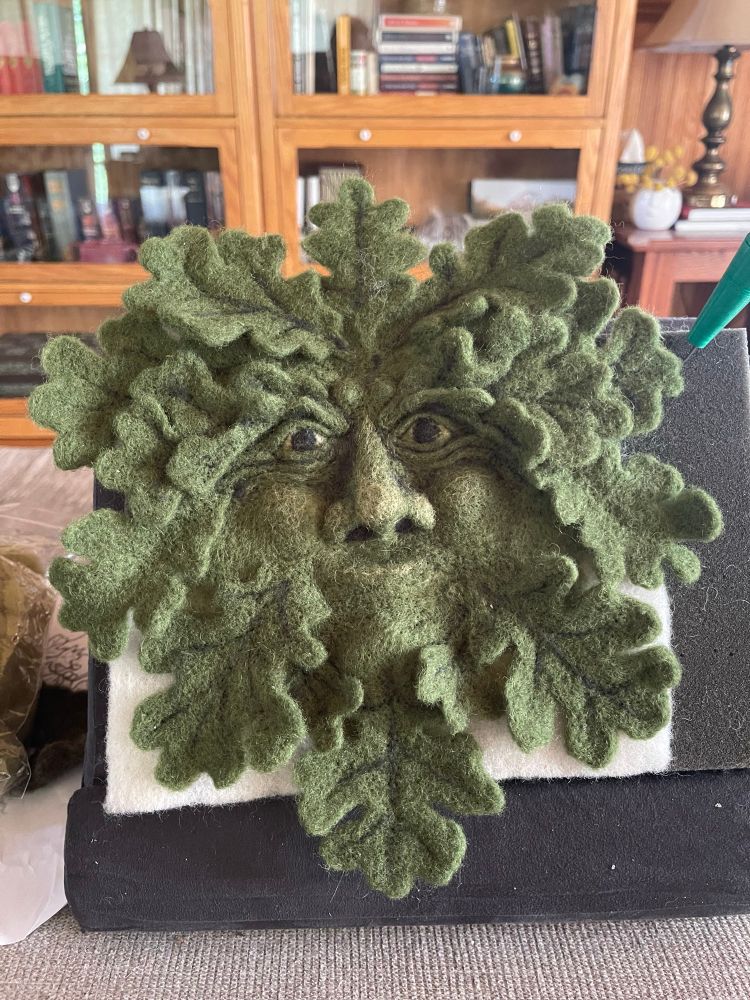 Wool needle felted sculpture of the “Green Man” in shades of green.  