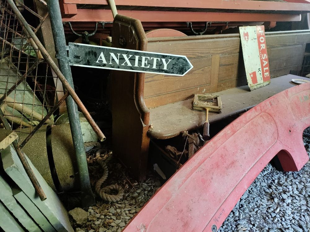 Pile of junk in an old shed, a signpost points towards anxiety