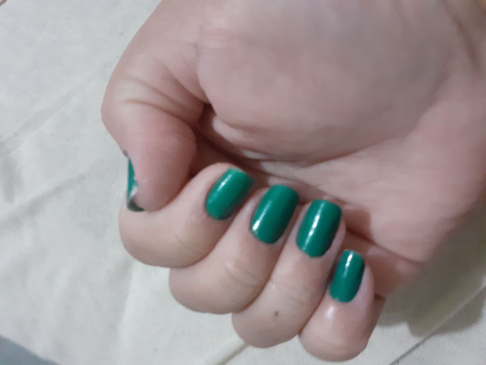 Foto das minhas unhas verdes e grandes, sendo que a foto é minha mão em cima da cama, com os dedos dobrados para dentro dela, mostrando as unhas 