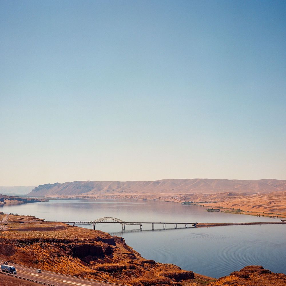 A shot looking out over the columbia river at Vantage WA. A bridge crosses the water and vehicles climb the freeway amid reddish rock