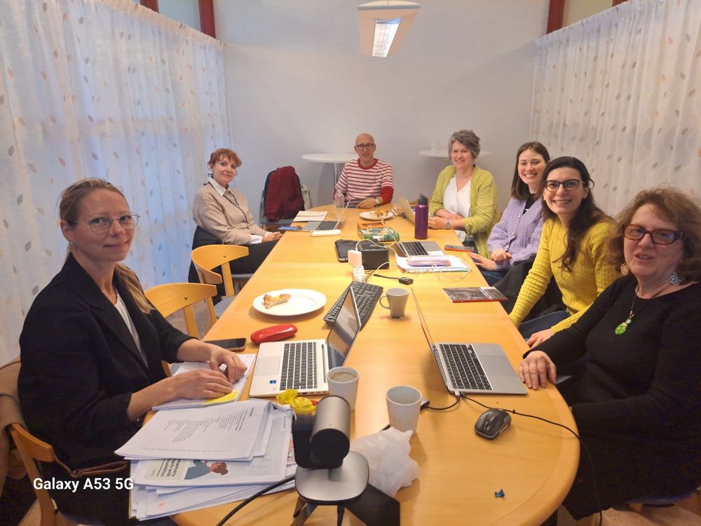 7 people sitting at a meeting table 