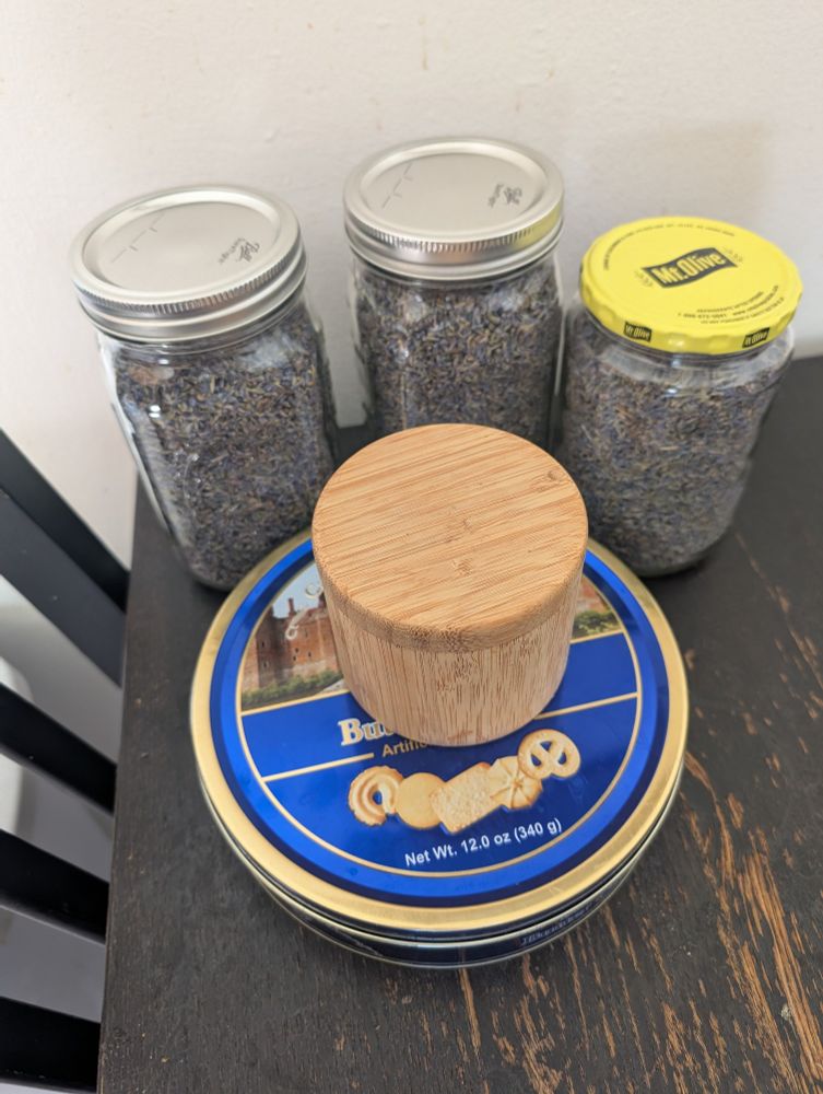 The same two quart mason jars from before, now joined by one large pickle jar, One tin that butter cookies came in, and one small bamboo tea container. All filled with lavender.