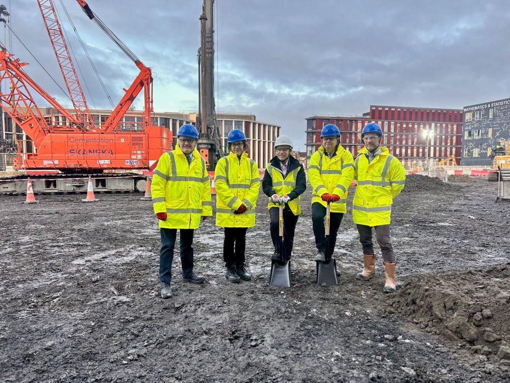Peter Haggarty (Executive Director of Estates), Moira Fischbacher-Smith (Vice Principal: Learning & Teaching), Frank Coton (Senior Vice Principal & Deputy Vice Chancellor), Professor Sir Anton Muscatelli (Principal and Vice Chancellor), and Carl Goodyear (Assistant Vice Principal) at the Keystone Ground-Breaking Ceremony. The group stand on the construction site in high-vis jackets and PPE, with shovels 'breaking ground'.