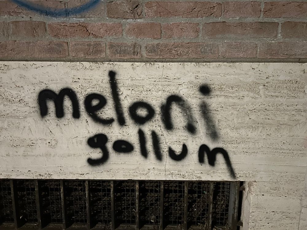Scritta nera con spray su pietra bianca:

meloni
gollum 