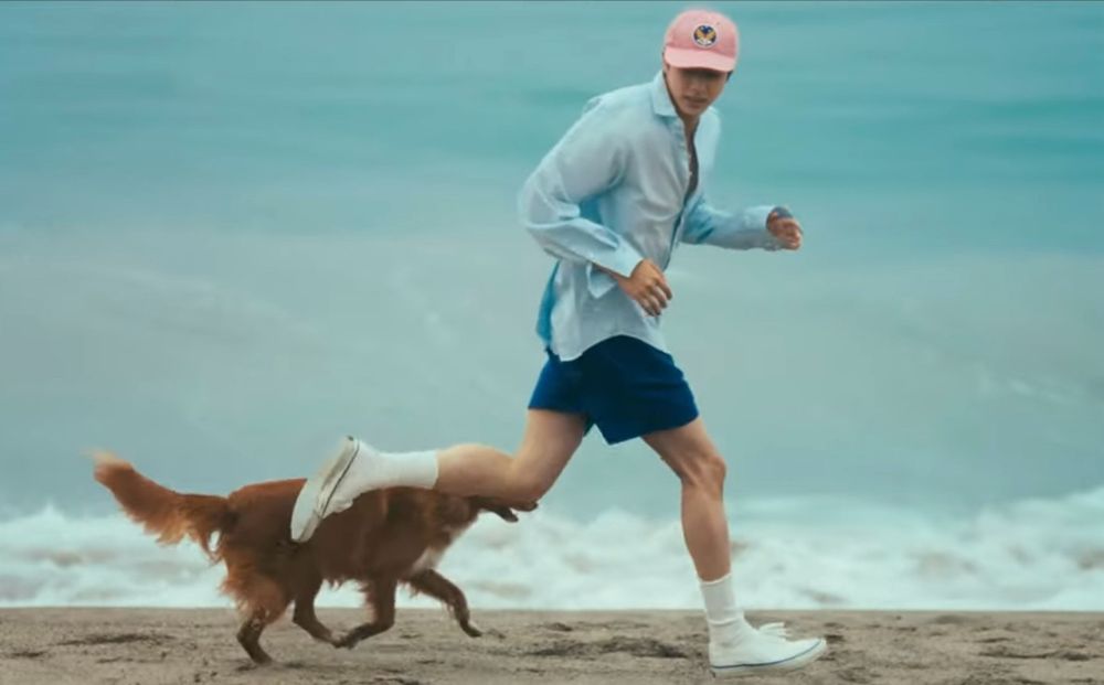 kim seokjin running an a beach wearing a pink baseball cap, a light blue button down shirt, white sock and sneakers, and REALLY GREAT BLUE SHORTS THAT SHOW OFF HIS SINEWY LEGS THAT LOOK VERY CHEWY AND GNAWABLE. Also there’s a really cute dog running next to him