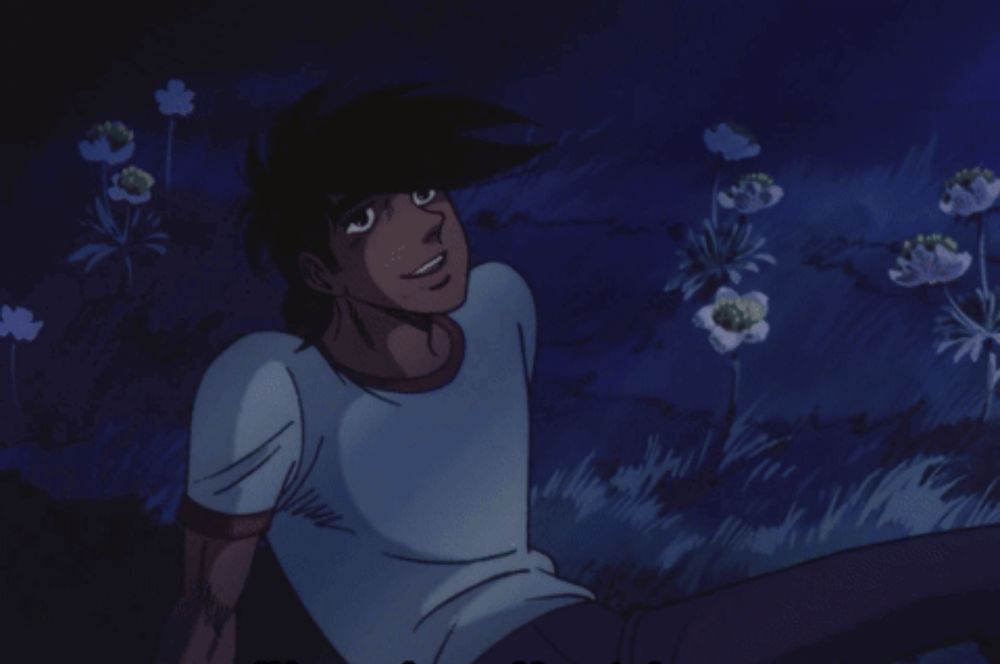 a man in a white shirt is sitting in a field of flowers at night