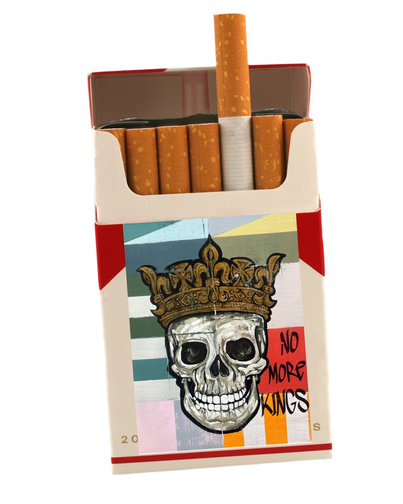 Artwork pop-art painting of a skull wearing a crown with No More Kings written on the image added to a pack of cigarettes. Original collab artwork from Hoey Xōchitl free to use under Creative Commons. 