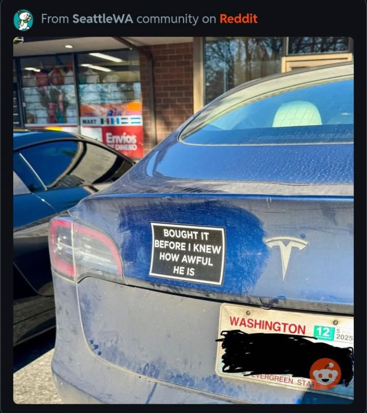 dusty blue tesla with a bumper sticker that reads, “bought it before i knew how awful he is”