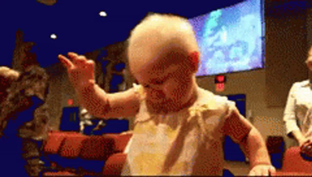 a baby is dancing in front of a large screen that says exit