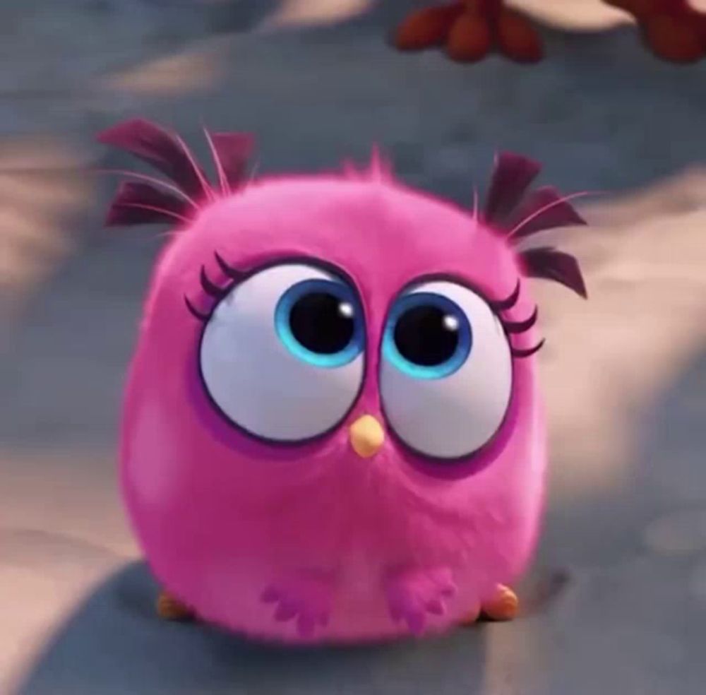 a pink angry bird with big blue eyes is sitting on the ground