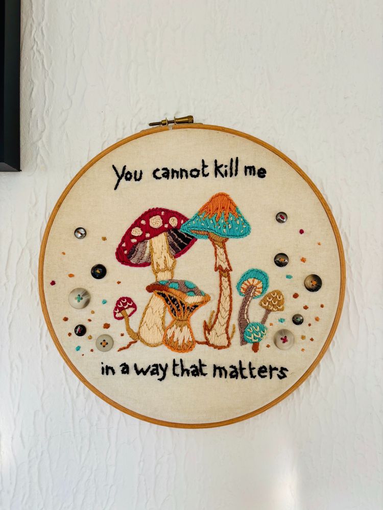Embroidered art of various fungi, with the phrase 'You cannot kill me in a way that matters'