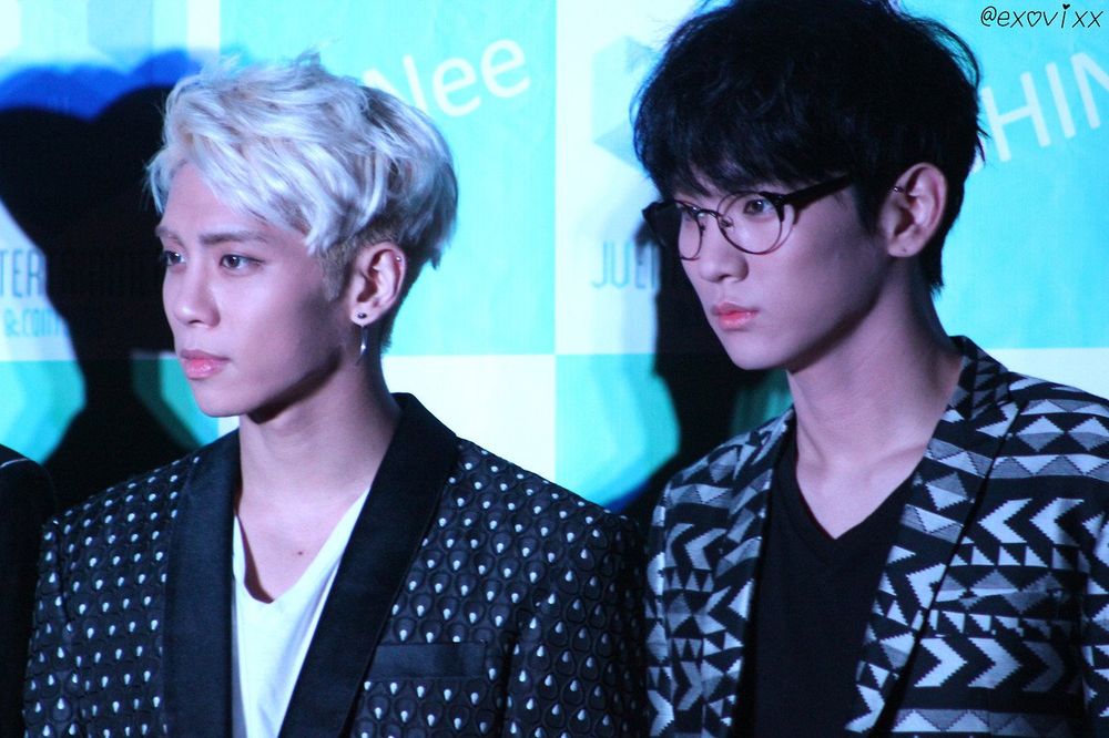Jonghyun with white hair and Key with black hair and glasses in black and white patterned suit jackets looking gorgeous 