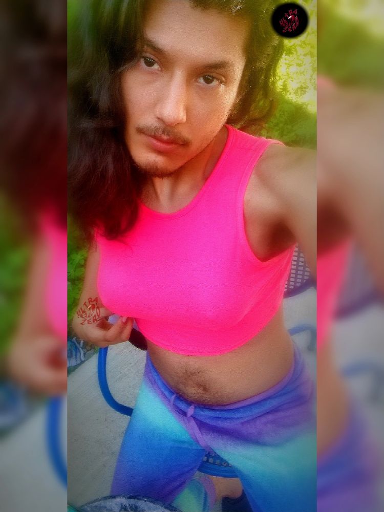 High angle shot of UltraEvilZero with his hair down wearing a sleeveless pink crop top & mix of purple & blue pj's while looking at the camera with "I want you look" 