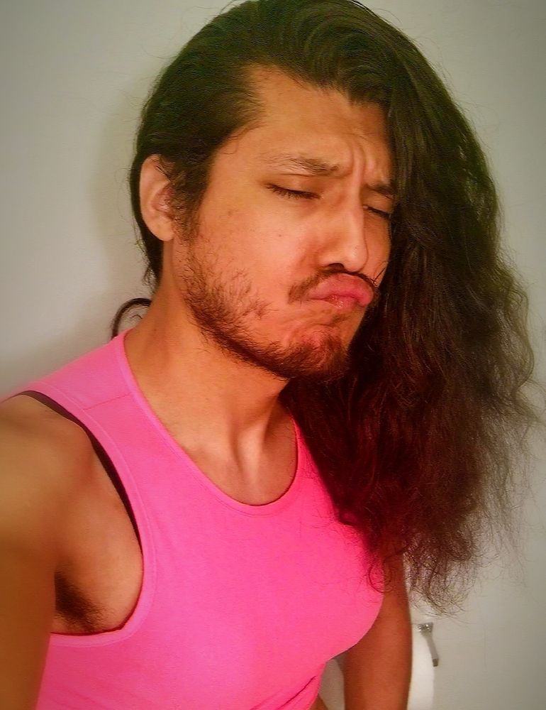 Bust shot of UltraEvilZero with his hair down & a pouty face. He is wearing a pink crop top with fake Titties inside them 