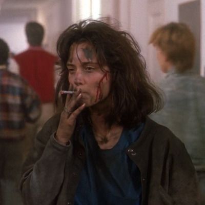 Winona Ryder as Veronica Sawyer, covered in soot and blood smoking a cigarette near the end of Heathers (1988).