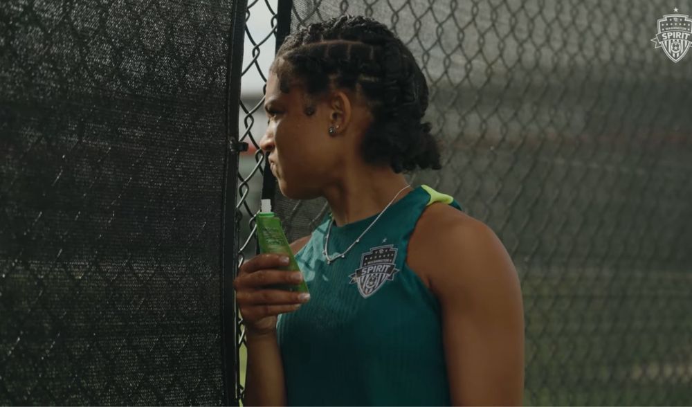 Croix making a face at something through a fence while holding a squeeze snack