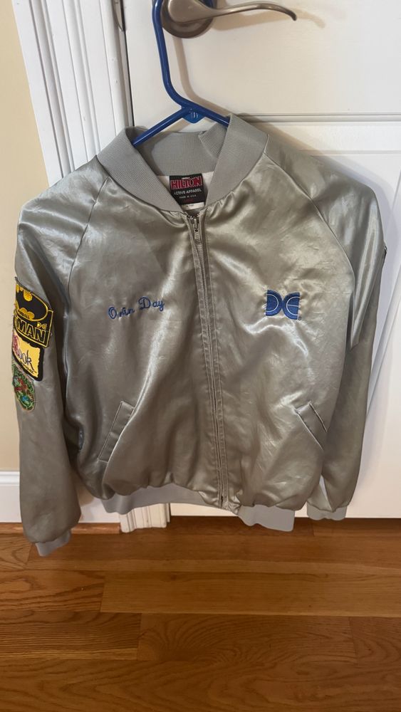 Silver Data East pinball jacket stitched with “Orin Day” and including patches for Batman, Hook, and Teenage Mutant Ninja Turtles