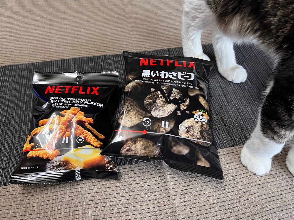 Netflixとのコラボで売り出されている食品シリーズから「黒いわさビーフ」の袋と「SQUID TEMPURA WITH BUTTER-SOY FLAVOR うまいかバター醤油風味　やみつきバターのうまみ！」の袋