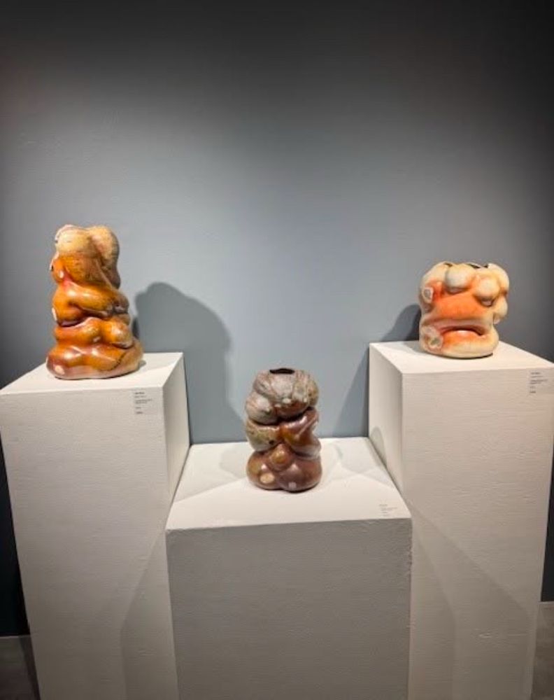Three organic abstract ceramic vessels displayed on pedestals 