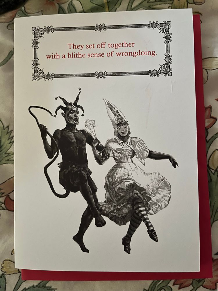 A Devilish jester and a witchy bride prance together. The front of the card reads, “They set off together with a blithe sense of wrongdoing.” 