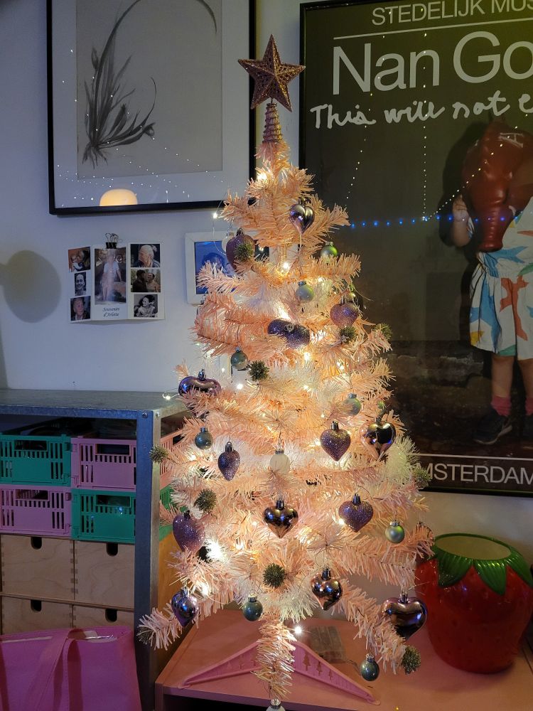Petit sapin de Noël rose décoré avec des boules en forme de cœur et une guirlande lumineuse 