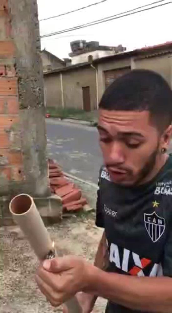 a man in a cam shirt is holding a pipe and a lighter in his hand .