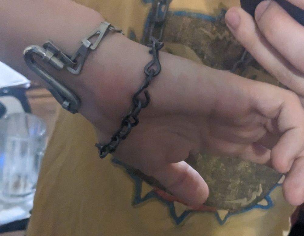 a closeup of the chain bracelets, showing the S hook that clamps the lighter one in place