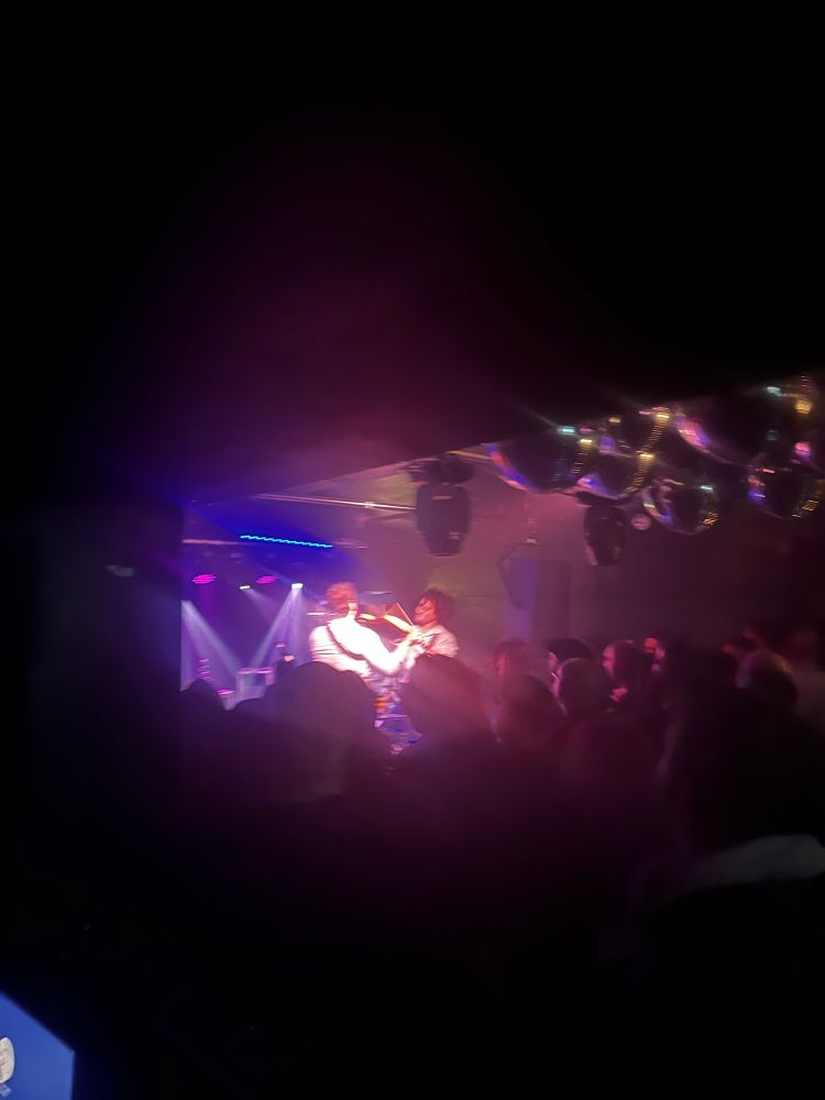 A terrible quality photo of ‘68’s drummer playing the guitarist’s guitar with drum sticks.