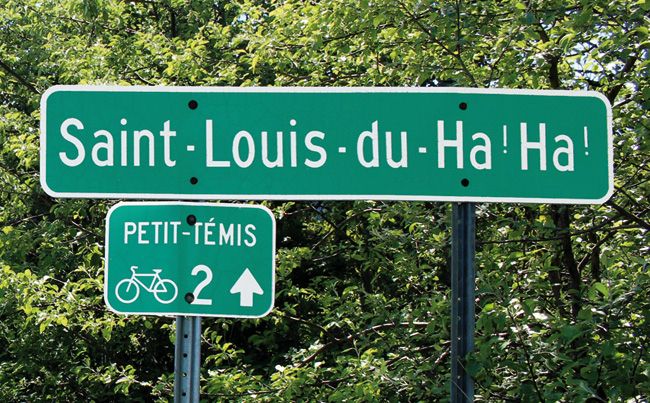 A green highway sign marking the parish of Saint-Louis-du-Ha! Ha! with an accompanying smaller sign for the nearby Petit-témis bicycle park trail.