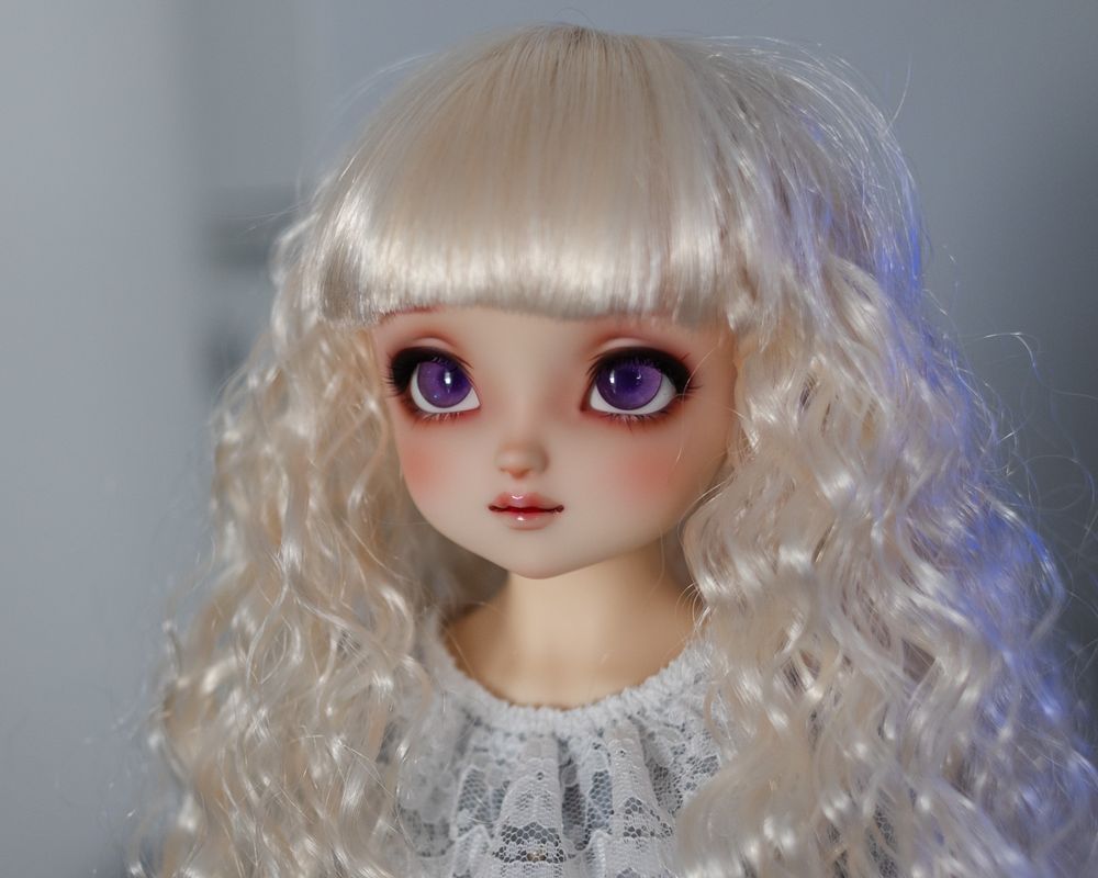 Portrait photo of a female ball-jointed doll with big beautiful purple eyes, wearing a light blonde wig with thick bangs and long curls.
