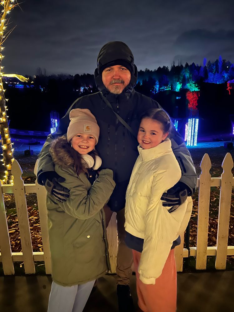 Me with my two girls outdoors with Christmas lights in the background