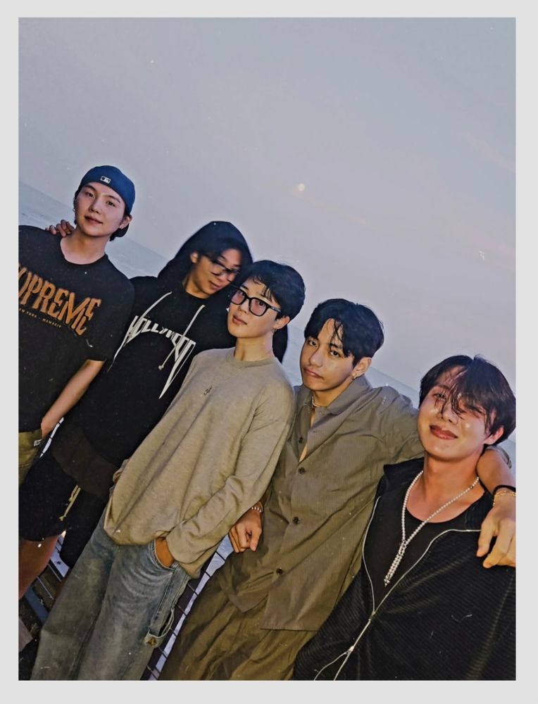 j.m insta post of 5 of 7 bts members. left to right, yoongi, namjoon, jimin, taehyung, hobi, standing grouped together on a beach with a pale misty moon in the background. they look like they just finished a nice dinner with drinks, or this could have been a grungy hit album cover from the 90s, who knows