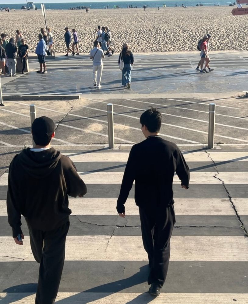 candid jimin photo posted my namjoon, photographer unknown. namjoon and jimin cross the street towards a beach, pic taken from behind. 