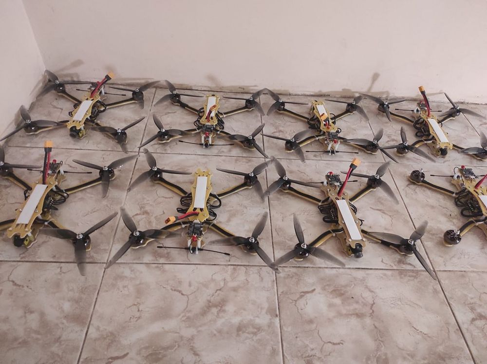 Eight drones aligned on the floor.