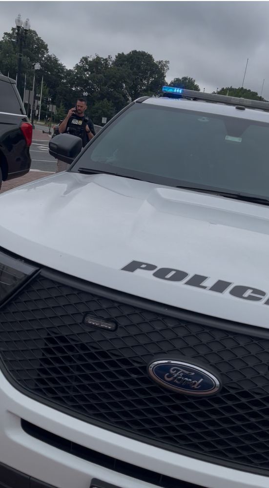 Another vacant but running with lights Amtrak Police SUV parked on ANOTHER pedestrian island outside Union Station while a federal LEO, standing next to an unmarked law enforcement SUV talks on his cell 