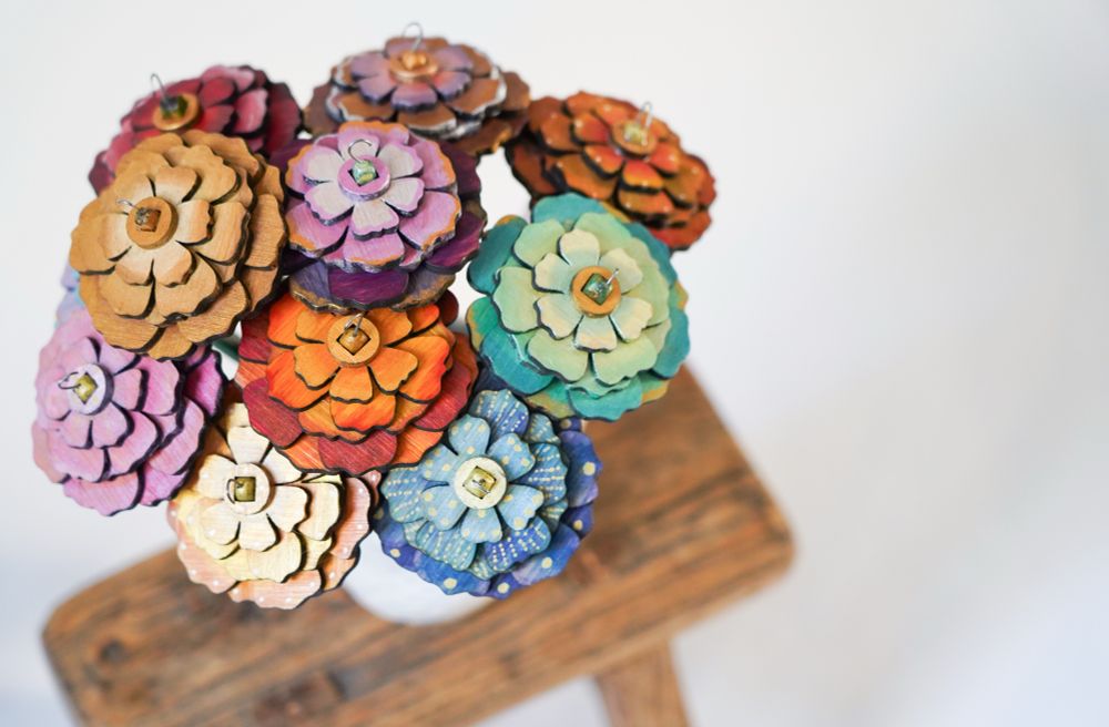 Hand painted spindles for making yarn, shaped as flowers and standing in a vase 