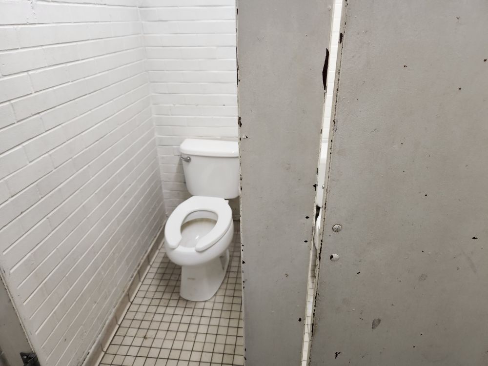 photo of dorty toilet stall with broken door