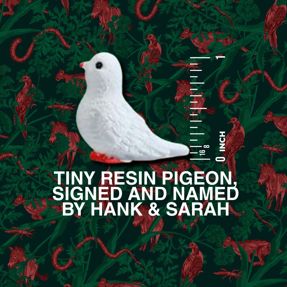 A photo of a tiny (1inch) resin pigeon next to a 1 inch scale bar on a bespoke forest background with red illustrations of endlings interspersed throughout. Text: "TINY RESIN PIGEON SIGNED AND NAMED BY HANK & SARAH"