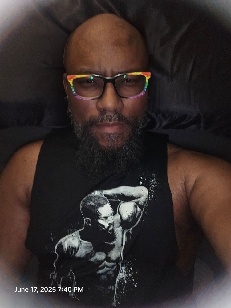 Poster wearing black stringer shirt with man holding up one arm 