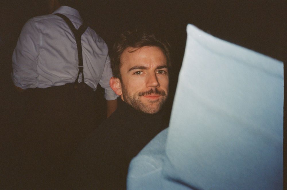 Christian in a black turtleneck behind some white object that I couldn’t even tell you what it is but Christian looks great 