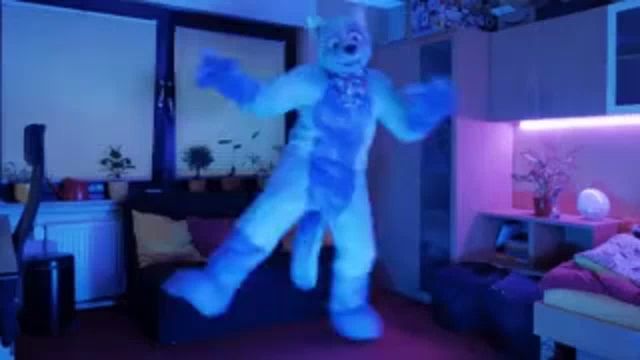 a person in a furry costume is dancing in a room with purple lights .