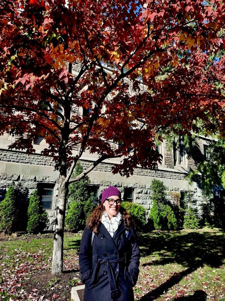 Lucia Rafanelli smiling and standing under a tree full of fall-colored leaves